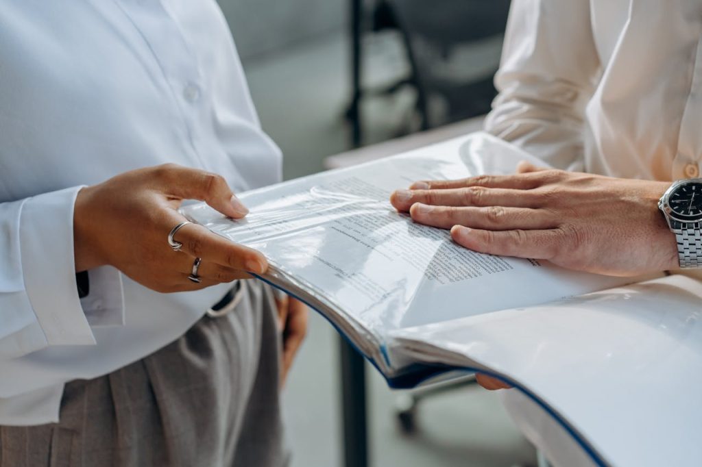 Two professionals examining business documents during a meeting indoors.